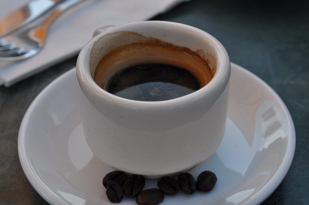 Tinto en pocillo blanco con granos de café