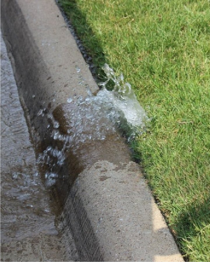 Water leaking over a curb from a broken irrigation line