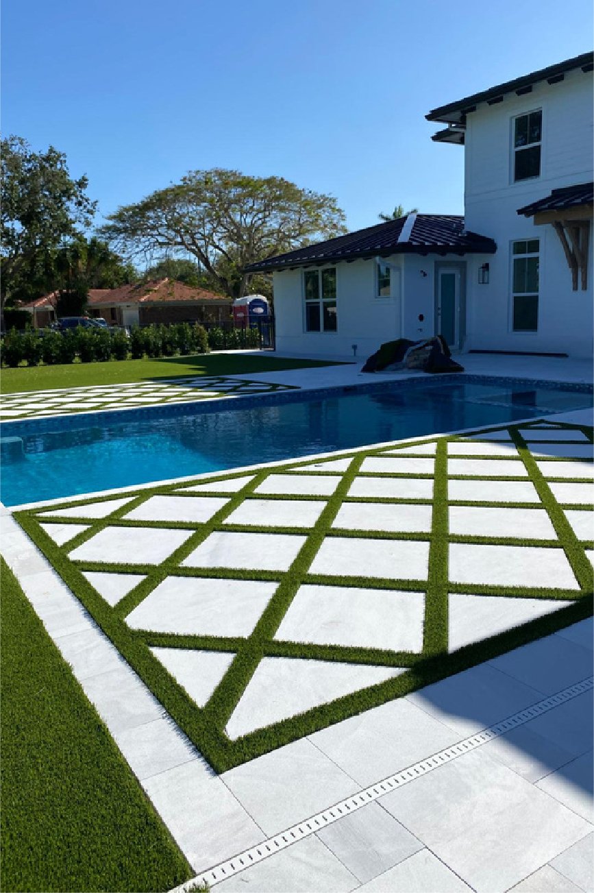Pool deck with artificial grass strips